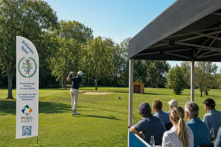Gäste im VIP-Zelt verfolgen einen Golfabschlag, der Ball fliegt nach rechts oben