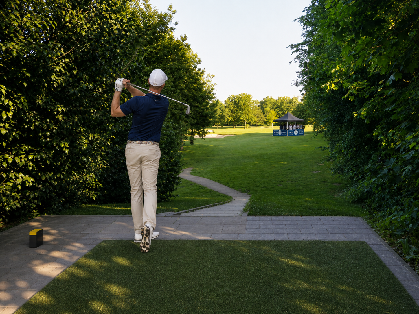 Golfer schlägt vom erhöhten Abschlag der Bahn 8 Richtung Grün mit vier Bunkern und VIP-Zelt.